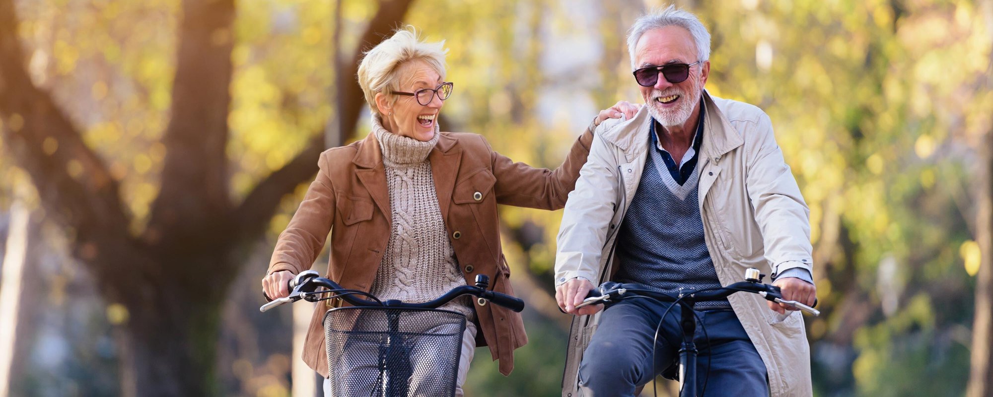 Old couple riding bikes in autumn