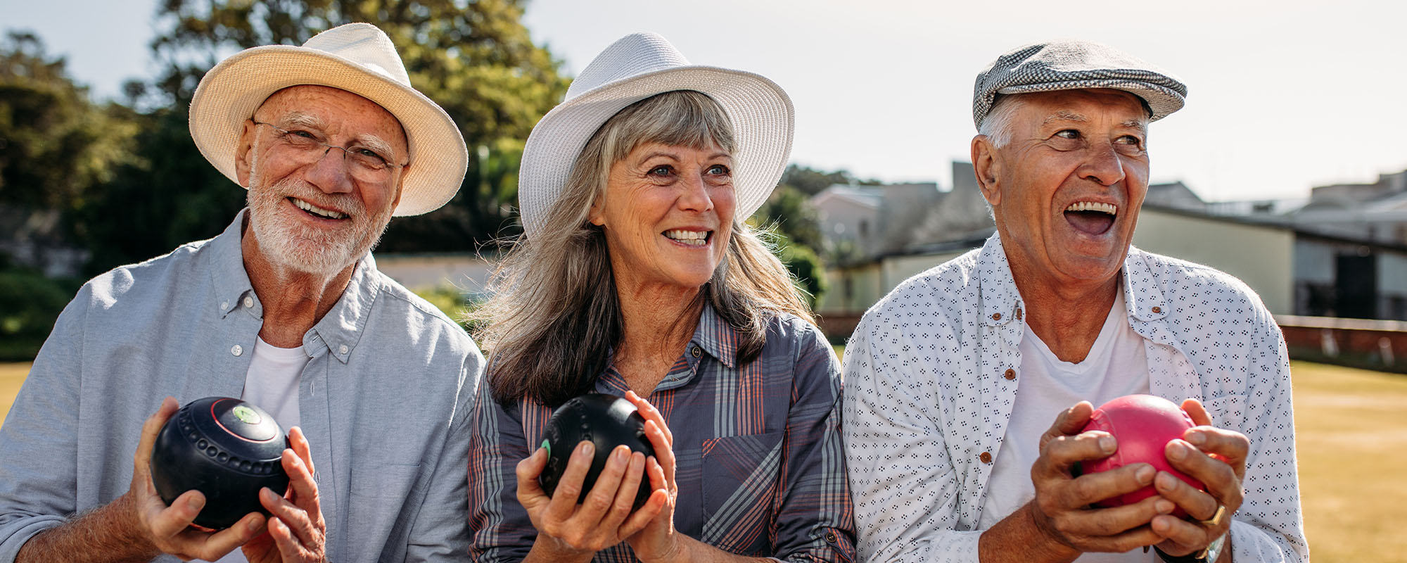 Senior people sitting together on a bench in a park holding boul